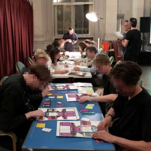 People at long tables playing a prototype of Peek